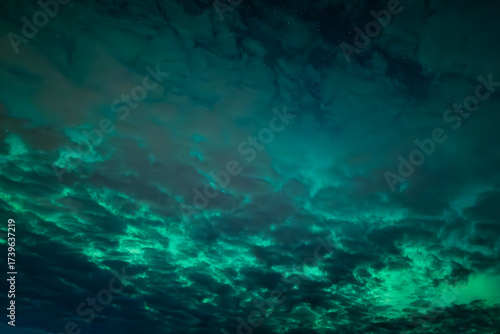 Northern lights dancing behinde the dark cloud over country landscape
