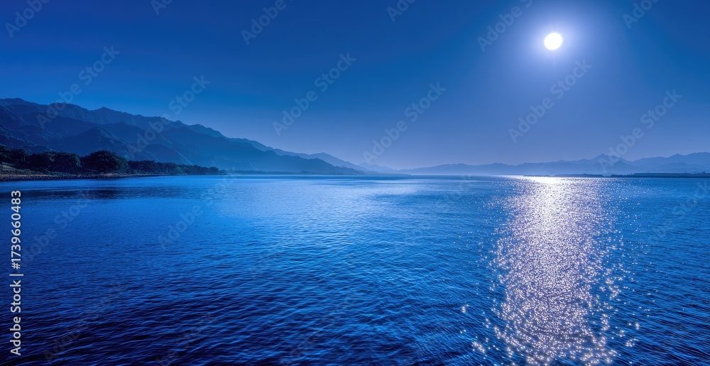 Fototapeta premium Serene nightscape depicts a shimmering lake reflecting the full moon and distant mountain range