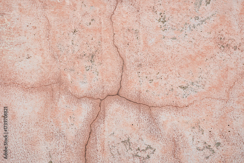 色褪せてヒビの入ったピンク色のコンクリート壁のテクスチャ。幾何学模様の背景素材