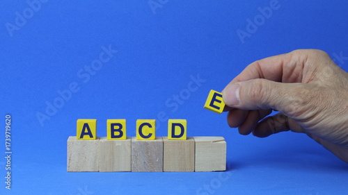 Due file di cubi di legno con le lettere A, B, C, D ed E, tenuti da una mano umana. Concetto di gestione e definizione delle priorità delle attività. Definizione delle priorità di qualsiasi attività.