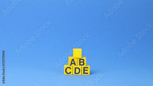 Blocchi di legno con le lettere A, B, C, D, E. Priorità delle attività e concetto di gestione. L'ordine di priorità in qualsiasi attività. Organizza la lista delle cose da fare a forma di piramide.