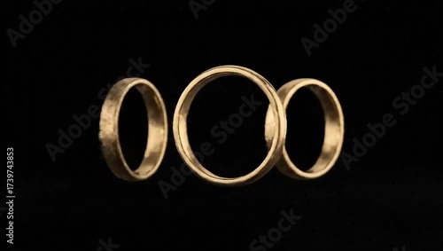 Gold wedding rings displayed against a black background  