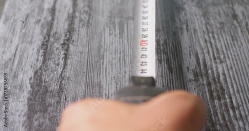First person view measuring a wooden surface with a tape measure