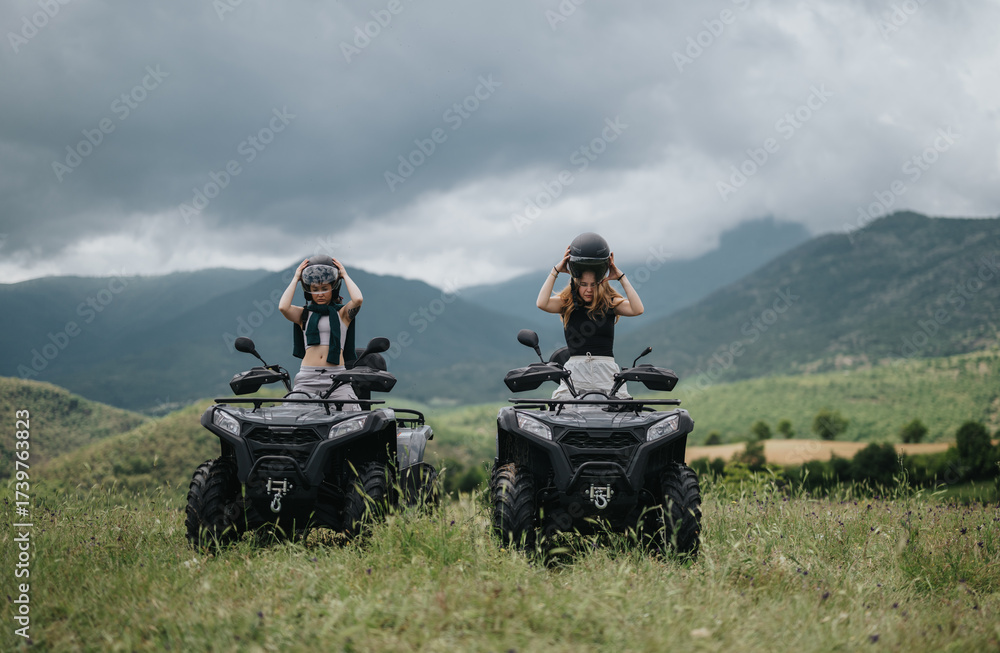 Obraz premium People enjoying a quad bike adventure outdoors in a lush, green valley. They are wearing helmets, emphasizing safety while embracing the spirit of exploration and outdoor fun in the scenic mountains.