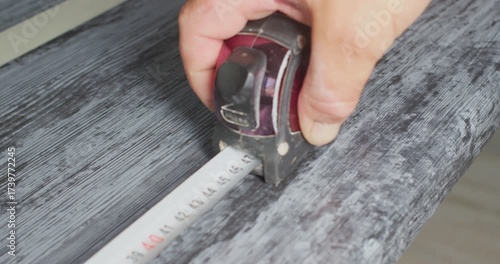 Worker using measuring tape on wooden surface