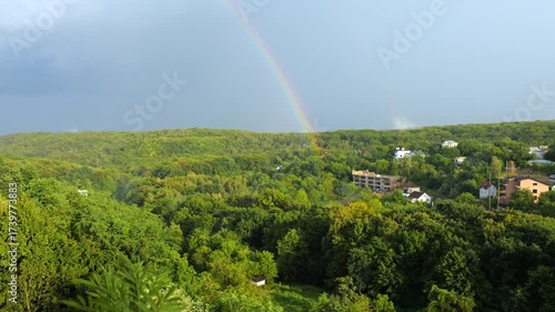 Rainbow against the background of forest and clouds.