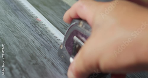 Worker using measuring tape on wooden surface