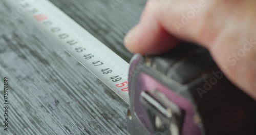 First person view measuring a wooden surface with a tape measure