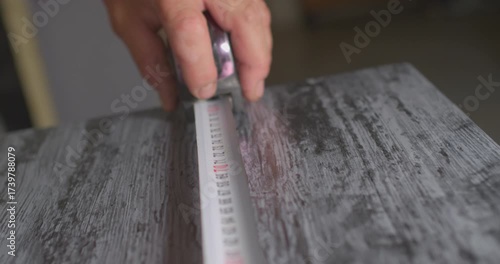 Carpenter measuring wooden board with tape measure
