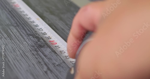 First person view measuring a wooden surface with a tape measure