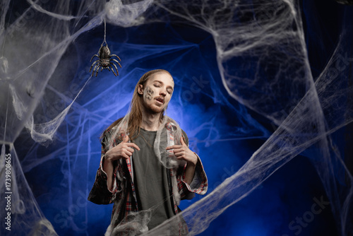 Konstfotografi Creepy scary zombie man with ugly makeup pointing at self promoting himself, indicating his choosing myself standing on spooky spider web background