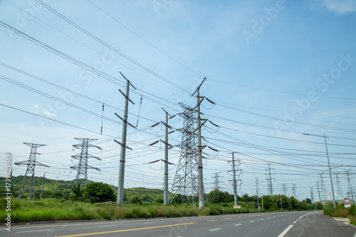 Φωτογραφία High-voltage transmission towers along a rural road under blue sky