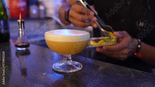 Bartender garnishing pisco sour cocktail with edible flower