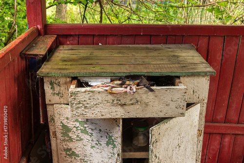 Old wooden table with a drawer in the veranda of an abandoned country house. Furniture with cracked paint
