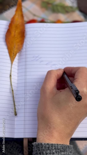 woman writes on a notebook in an autumn park