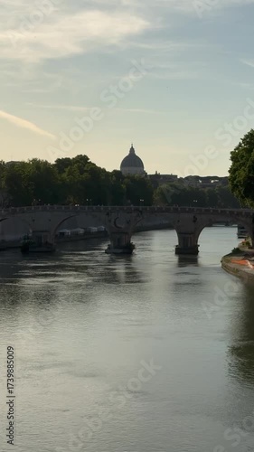 The Tiber River flows under the Ponte Sisto bridge in central Rome. In the background is the dome of St. Peter's.