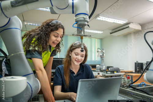 Robotics Education: Female Engineers with a Laptop, Focused on a Robotic Arm Female Engineers Working on the Programming of a Robotic System Two Women Collaborating on a Robotics Engineering Project