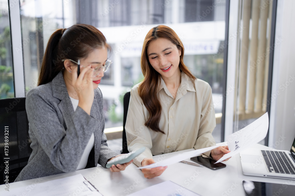 Fototapeta premium Asian business women collaborate office financial analysis reviewing data discussing corporate strategy professional meeting productivity workspace solution
