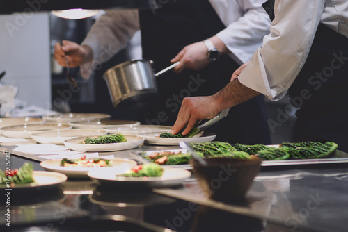 Billede på lærred Chefs in a professional kitchen plating gourmet appetizers with precision, demonstrating teamwork and the final stages of a fine dining experience