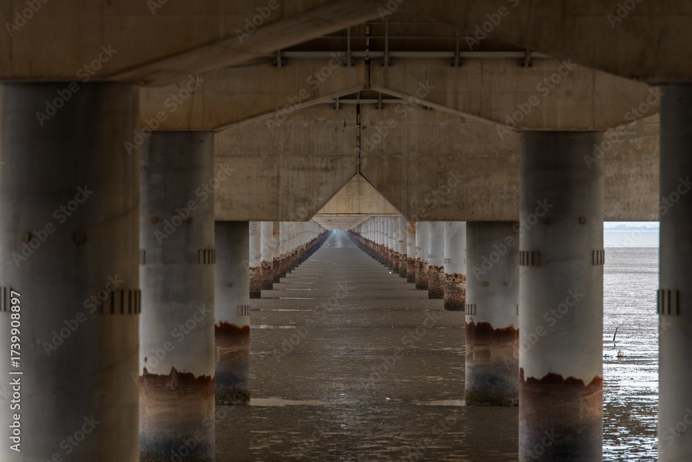 Obraz premium bridge columns on mud flat beach and sea