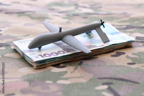 Wallpaper Mural Unnamed grey toy drone and ukrainian money bills on camouflage fabric close up Torontodigital.ca