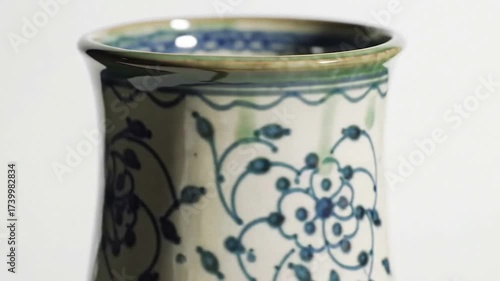 Close-up of a traditional blue and white ceramic vase with a hand-painted floral motif and a green glazed rim.