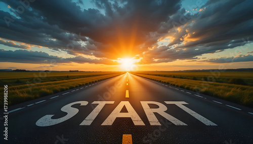 Motivational Word 'START' Painted on an Empty Asphalt Road Leading to a Bright Sunset Horizon in a Dramatic Landscape for Business Goals and New Beginning Concepts