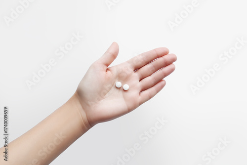 Hand holding two small round pills