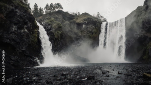 A dramatic waterfall cascades down rocky cliffs, surrounded by misty, overcast scenery