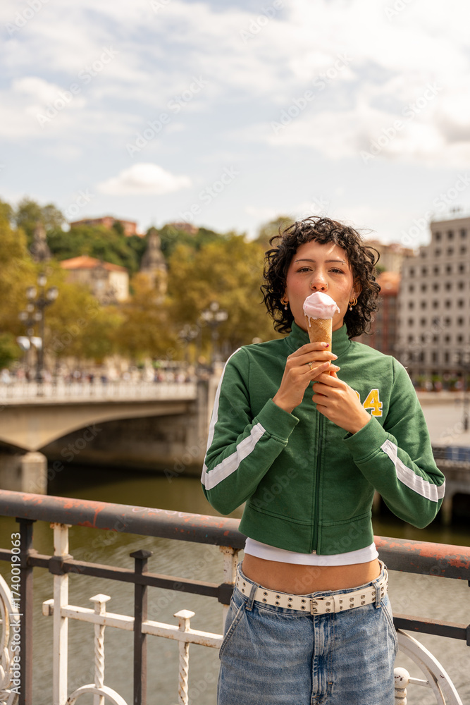Fototapeta premium Young woman enjoying ice cream on a bridge in bilbao