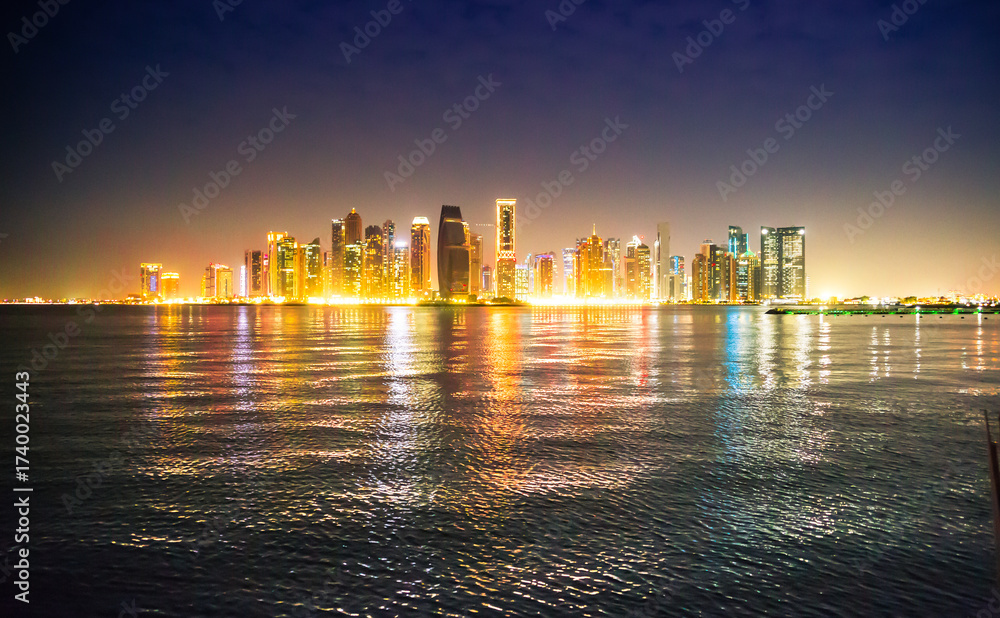 Fototapeta premium Beautiful night view of Doha city, skyscrapers of financial area and reflection in bay water. Qatar