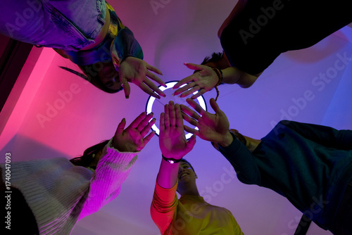 Friends reaching out hands with vibrant lighting in an energetic indoor setting