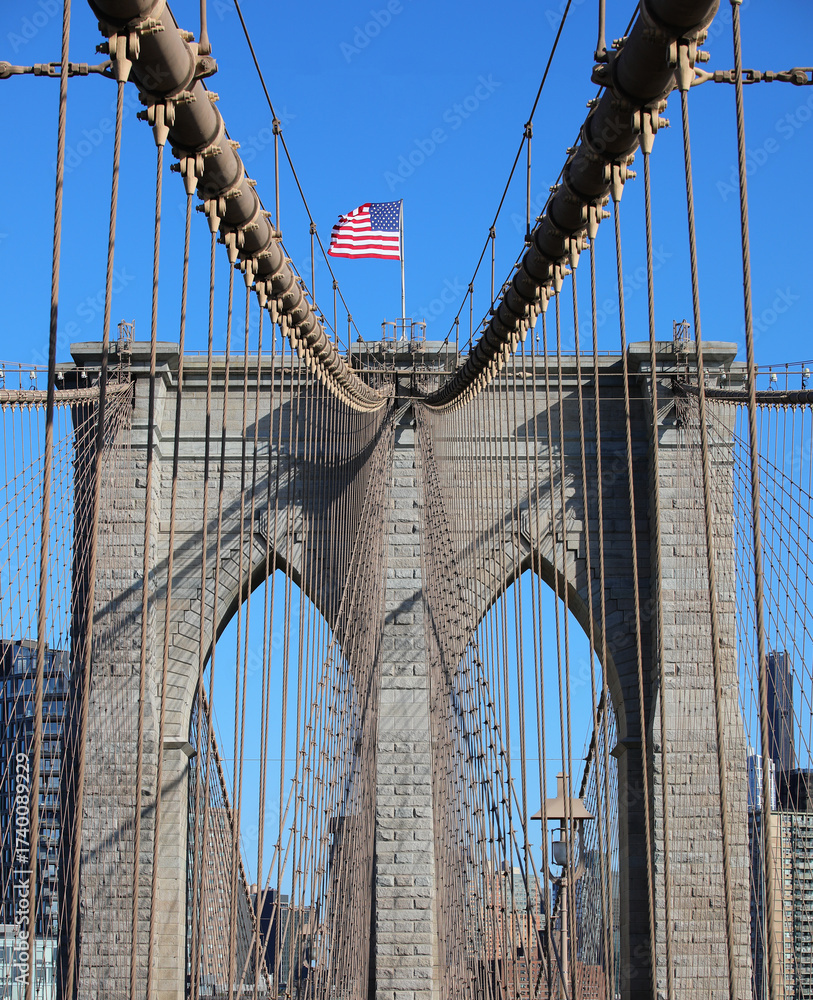 Fototapeta premium New York city with Large American Flag on the top of Brooklyn Bridge and steel cables