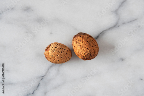 Close-up of almonds with their shells on white marble