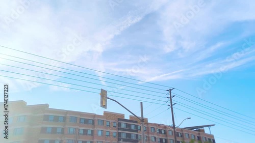 Apartment building rooftop view with power lines under a bright blue sky, capturing city living and urban development, perfect for real estate or construction projects