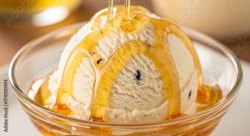 A delicious scoop of creamy vanilla ice cream in a glass bowl with golden honey being drizzled over the top