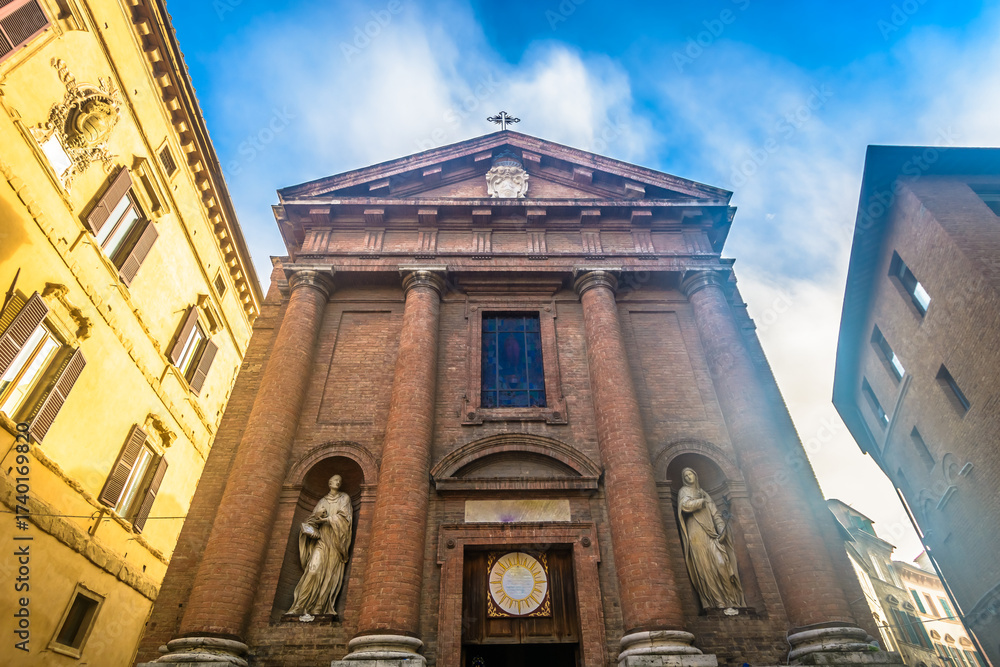 Naklejka premium Vivid photo of a colorful street in Siena historic center showing traditional Tuscan buildings, stone facades, flags, narrow alleyways and charming medieval atmosphere in Italy