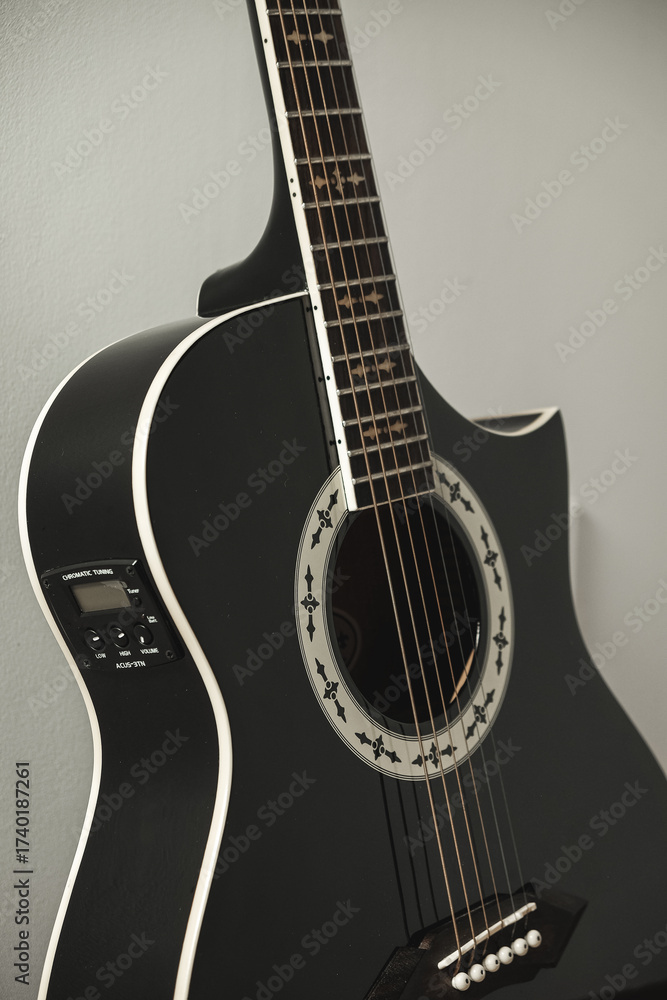 Fototapeta premium Elegant black guitar rests against a soft backdrop, showcasing its unique design