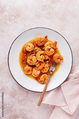 Savory shrimp dish served in a white plate with flavorful sauce and herbs