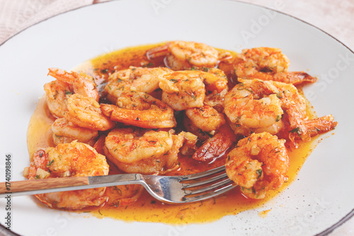 Savory shrimp dish served in a white plate with flavorful sauce and herbs
