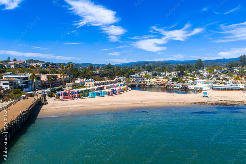 Fototapeta premium Aerial perspective of Capitola beach town, showcasing coastal buildings, sandy shores, and the Pacific Ocean under clear skies in California.