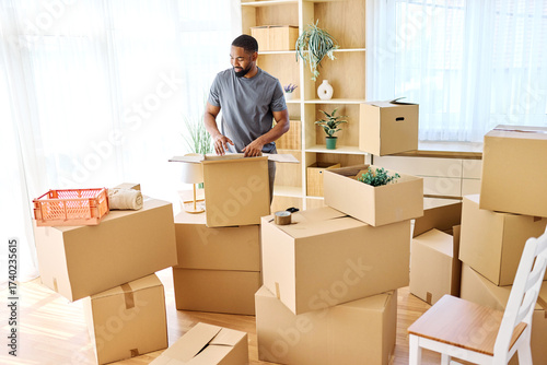 Photos Portrait of a young man guy unpacking boxes after moving in and relocation in a