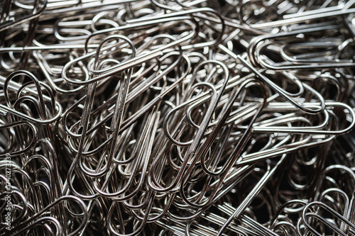 A chaotic yet captivating close-up of numerous metallic paper clips, highlighting their intricate shapes and textures. Ideal for office, creativity, and abstract themes