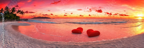 Dramatic pink and red sunset over a beach with two hearts in the water