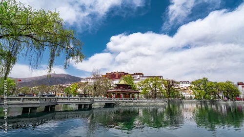 Potala Palace Lhasa Tibet reflected in lake waters with willow trees and dramatic sky time lapse view