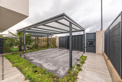 Open carport with a dark green painted metal frame and a sloping tiled roof.