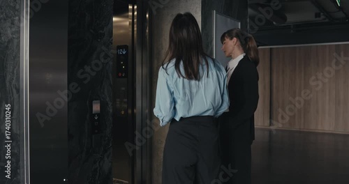 Wallpaper Mural Two professional office workers girls call the elevator and enter it while chatting. Office girls in business clothes chatting and entering the elevator Torontodigital.ca