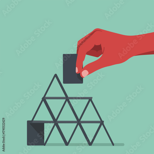 Hand carefully placing a dark card on a house of cards structure