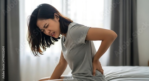 Woman Suffering from Lower Back Pain While Sitting on Bed