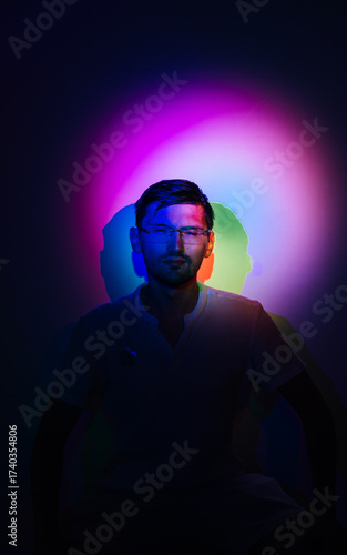 Portrait of a squinting man in neon colorful light.